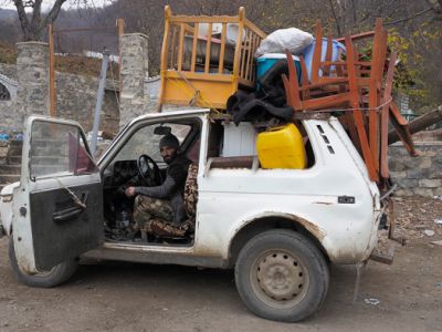 Мужчина сидит в своей машине, нагруженной вещами, готовясь покинуть район, который передан  Азербайджану. Дмитрий Ловецкий / AP